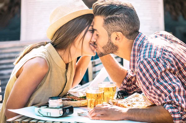 Couple in love kissing at bar eating local food on travel excursion - Young happy man and woman drinking beer by street bar - Relationship concept with lovers during first date - Warm sunny filter — Stockfoto