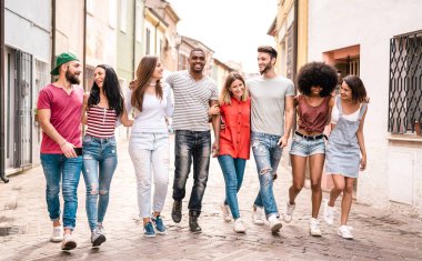 Multiracial millennial friends walking in city center - Happy guys and girls having fun around old town streets - University students on travel vacations  - Warm desaturated filter clipart