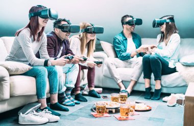 Evde vr kulaklıkla oynayan arkadaşlar - Sanal gerçeklik ve 3d video oyunlarında eğlenen insanlarla giyilebilir teknoloji konsepti - Z nesli dijital trendler - parlak masmavi filtreye sahip sol adama odaklanın