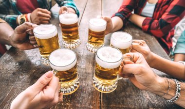 Arkadaşlar, bira barında bira bardaklarını tokuştururken el ele tutuşuyor - Gençlerin birlikte eğlendiği ve kaliteli bira barında eğlendiği meşrubat konsepti - Sağ alt bardağa odaklan - Sıcak filtre