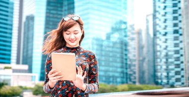 Young asian woman using electronic device at modern city  - Technology lifestyle concept with girl having fun with pc tablet device - Influencer digital trends on bright azure filter and sun halo clipart
