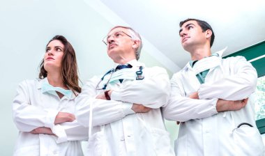 Genç ve kıdemli doktorlar hastane kliniğinde koronavirüs salgınına karşı savaşmaya hazır - dünya çapında virüs salgını hakkındaki tıbbi acil durum kavramı - parlak nötr filtre