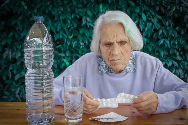 Retrato de una hermosa mujer de 90 años con pastillas en la mano. Mujer anciana, con dolor de cabeza, problema emocional, demencia, trastorno mental, frustrada. Concepto de anciano — Foto de Stock