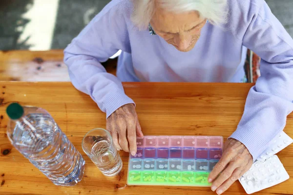 Primer plano de la hermosa mujer de 90 años con pastillas en la mesa. Mujer anciana, con dolor de cabeza, problema emocional, demencia, trastorno mental, frustrada. Concepto de anciano . — Foto de Stock