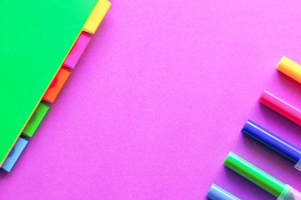 Ноутбук с разделенными цветовыми частями и бивнями на фиолетовом бумажном фоне. Волшебные цвета канцелярских товаров. Канцелярские принадлежности . — стоковое фото