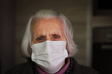 Hijyenik maske takan yaşlı bir kadın. Evde kal. COVID-19 kavramı.