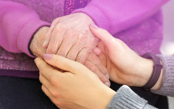 Mani di giovani donne adulte e anziane. Anziani e giovani che si tengono per mano fuori. Concetto anziano — Foto Stock