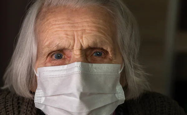 Señora mayor con máscara facial higiénica. Una anciana con ojos asustados. COVID-19 concepto, distancia social — Foto de Stock