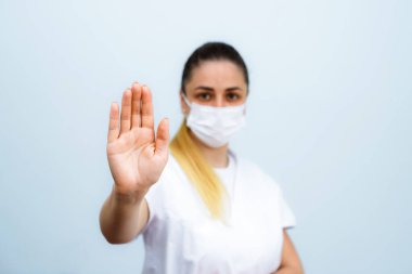 Palmo della mano 'yu kapatın, e la ragazza sfocata sullo sfondo. Sosyal uzaklığın sembolü. Sağlık hizmetleri kavramı