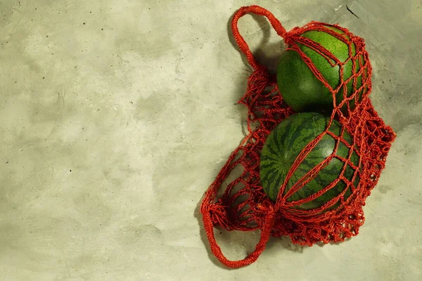 Wicker bag string bag with two striped watermelons. — Stock Photo, Image