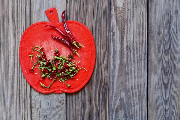 Kırmızı biberler ve kuyrukları plastik bir tahtanın üzerinde..
