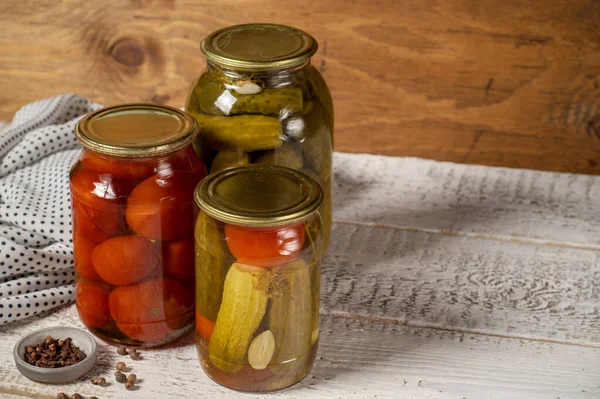 Jars with assorted fermented cucumbers and tomatoes with seasonings. — Stock Photo, Image