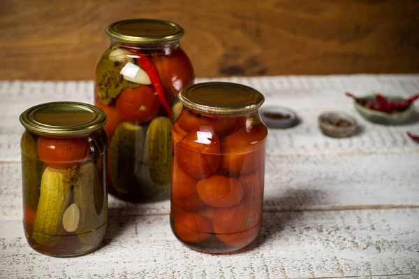 Jars with assorted fermented cucumbers and tomatoes with seasonings. — Stock Image Jars with assorted fermented cucumbers and tomatoes with seasonings. Stock Photo