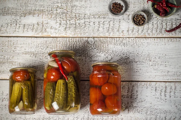 Jars with assorted fermented cucumbers and tomatoes with seasonings. — Stock Image Jars with assorted fermented cucumbers and tomatoes with seasonings. Royalty Free Stock Photos