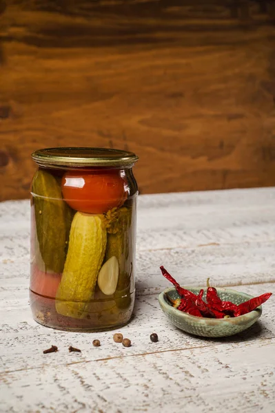 Jar of fermented cucumbers and hot pepper sauce pot close-up. — Stock Photo, Image