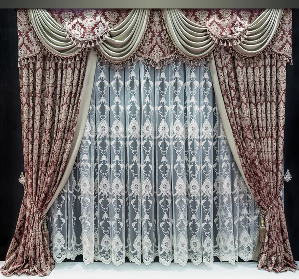 Luxurious interior design, curtains in burgundy colors, a light tulle and a pelmet