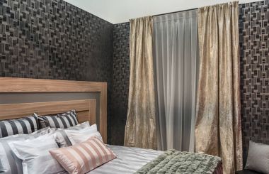 Yatak odası doğal malzemeler ile modern tasarımı. Bir geometrik desen, çizgili ve düz vintage perdeler, yatak çarşafları ile karanlık duvarlar.