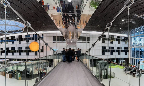 Moscú. 15 de febrero de 2017. Centro de Innovación Skolkovo. Excursión alrededor de Technopark. La gente se para en un puente colgante admirando una hermosa vista de la sala y los pabellones . — Foto de Stock