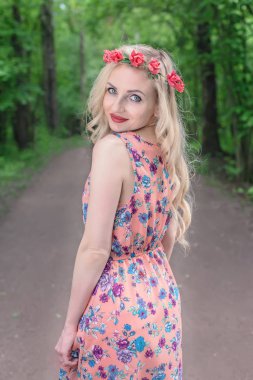 Bir çelenk gül başında genç bir sarışınla orman yolu bir güzel yaz günü elini kolunu sallaya dönüyor