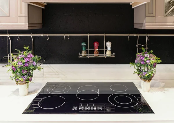 Modern kitchen in high-tech style. A kitchen apron made of wood plates painted black. Modern hob built into the marble countertop.