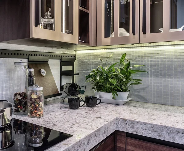 Comfortable and functional kitchen in high-tech style. Marble countertop and apron from ceramic mosaic tiles.