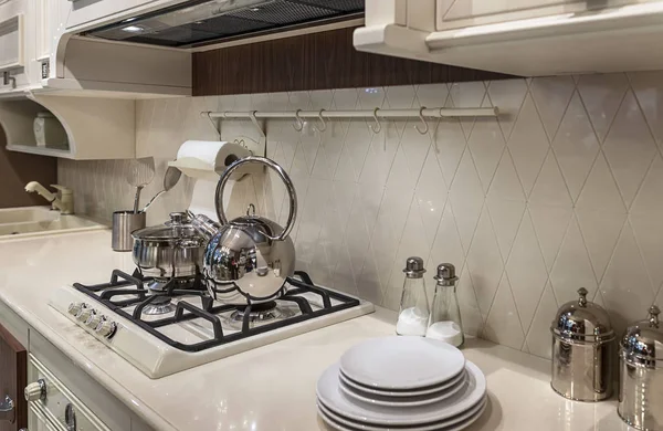 Luxurious milk-white kitchen in classic style. Gas cooker and shiny metal dishes.