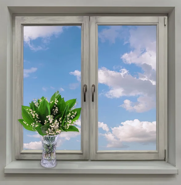 Την άνοιξη. Ένα παράθυρο με θέα το γαλάζιο του ουρανού και το φως σύννεφα. Βάζο με κρίνα της κοιλάδας στο περβάζι. — Φωτογραφία Αρχείου
