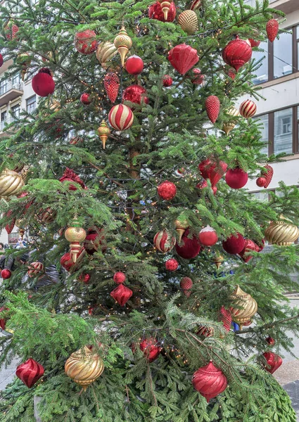 Beautiful New Year's toys, balls and garlands hang on a live Christmas tree on the street — Stock Photo, Image