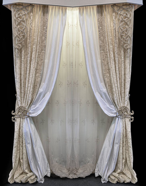 Interior in the palace style. Combined curtains made of golden velor and white satin fabric. Tulle with floral ornament. Knitted pattern from decorative cord