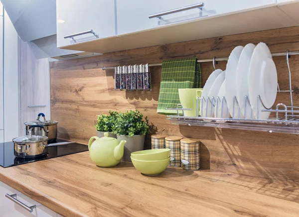 Fragmento del interior de una cocina moderna con fachadas blancas brillantes, con una mesa de madera y delantal — Foto de Stock