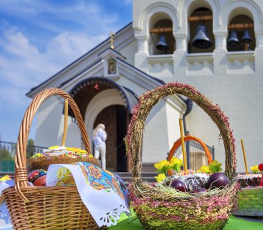 Hasır sepetlerdeki Paskalya hediyeleri kilisenin girişindeki masanın üstünde. Renkli yumurtalar, Paskalya pastaları ve paskalya pastası.
