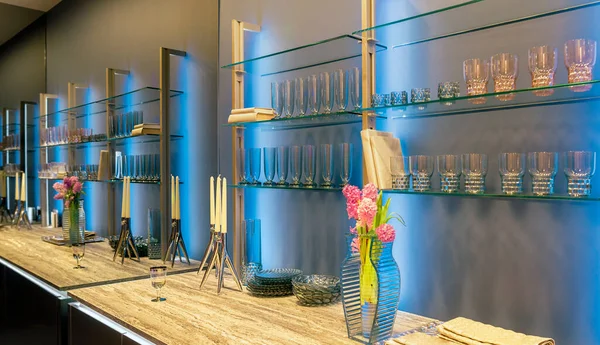 Aynalı duvarları ve iç eşyaların ritmik yansıması olan modern bir mutfağın parçası.