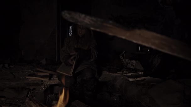 一个肮脏的无家可归的小女孩在篝火边的废墟里看书 — 图库视频影像