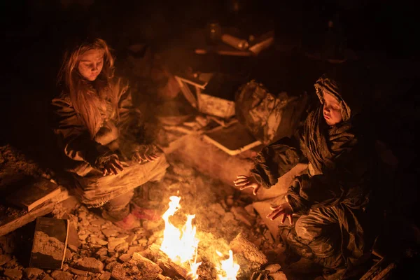 キャンプファイヤーの近くに座っているホームレスの子供たち ロイヤリティフリーのストック画像