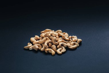 Karanlık bir arka planda, soyulmuş fındıklar dağınık. Siyah arkaplana fındık döküldü