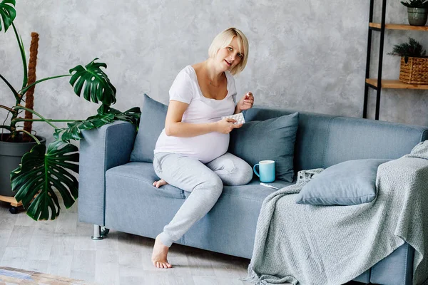 Young Pregnant Blonde White Shirt Gray Trousers Sits Gray Sofa — Stock Photo, Image