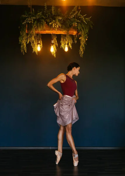 Een moderne ballerina, een heel mooi jong brunette meisje in een donkerrode bordeaux maillot in een badpak en een tule rok — Stockfoto