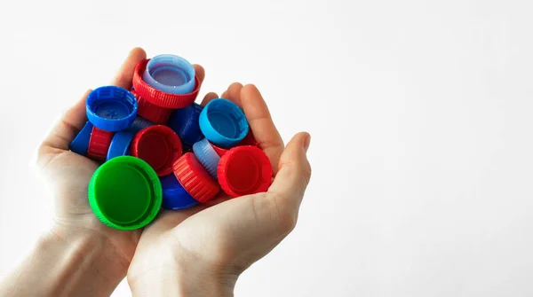 Ellerinde bir avuç dolusu plastik kaplama var. Plastiğin ayrı toplanması ve geri dönüşümü kavramı. Yakın plan. Çöpleri ayıklıyorum. Web sitesi veya sosyal ağlar için yatay afiş şablonu.