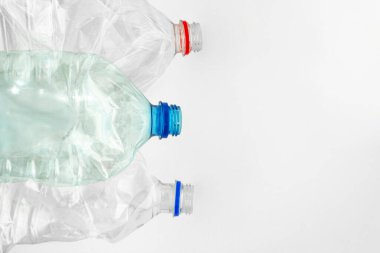 Geri dönüşüm ve ayrı platik koleksiyonu. Beyaz arka planda buruşmuş plastik şişeler. Mesaj için yer var. Gezegenin plastik kirliliği, çevresel sorunlar.