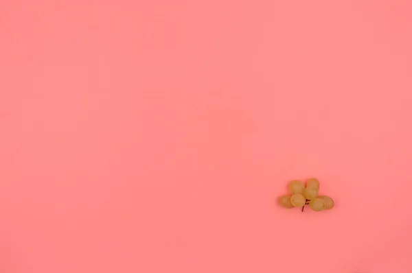 Pembe arka planda beyaz üzümler.