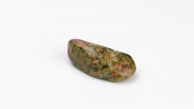 Beyaz arka planda mineral unakit. Döndürme. Epidosit, Unakit. Dekoratif ve süs taşı. Manzarayı kapat. Mücevher. Klitoterapi.