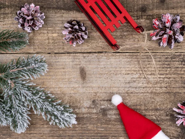 Karların altında Noel ağacı dalları, koniler, kırmızı kızaklar 