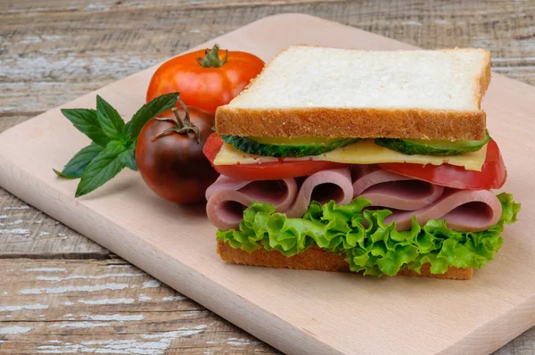 Un delicioso sándwich con salchichas, queso, tomates y lechuga . — Foto de Stock