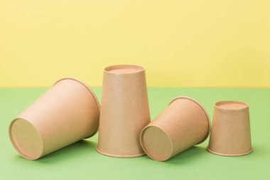 Yeşil ve sarı arka planda kağıt bardaklar. Çevresel tek kullanımlık tablo takımı.