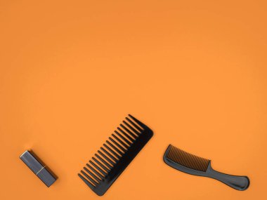 Turuncu arka planda taraklar ve ruj. Kadın aksesuarları.