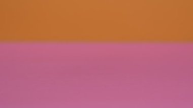 Tabletler ve kapsüller pembe ve turuncu arka plana yağdı.