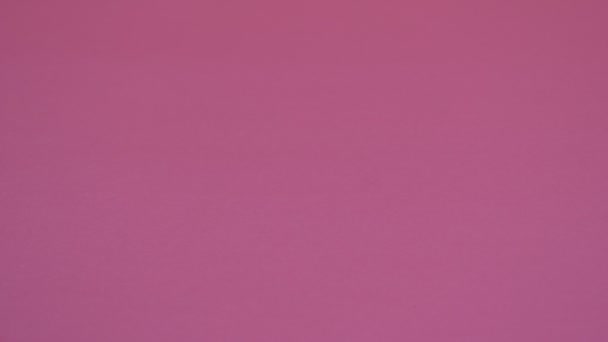 Homöopathisches Granulat ist auf rosa Hintergrund verstreut. — Stockvideo