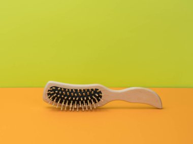 Parlak turuncu ve yeşil arka planda ahşap tarak. Saçı tarama konusu..