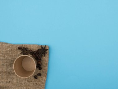 Mavi arka planda kahve için kağıt bardak. Kahve çekirdekleri ve yıldız anasonu..