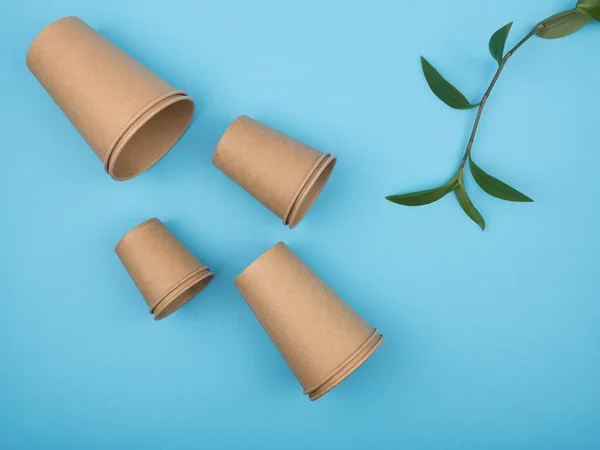 Stylish recyclable paper tableware on a blue background. The view from the top. Disposable cups.